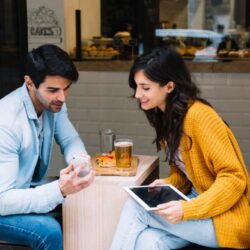 couple-cafe-looking-smartphone-screen-1050x700